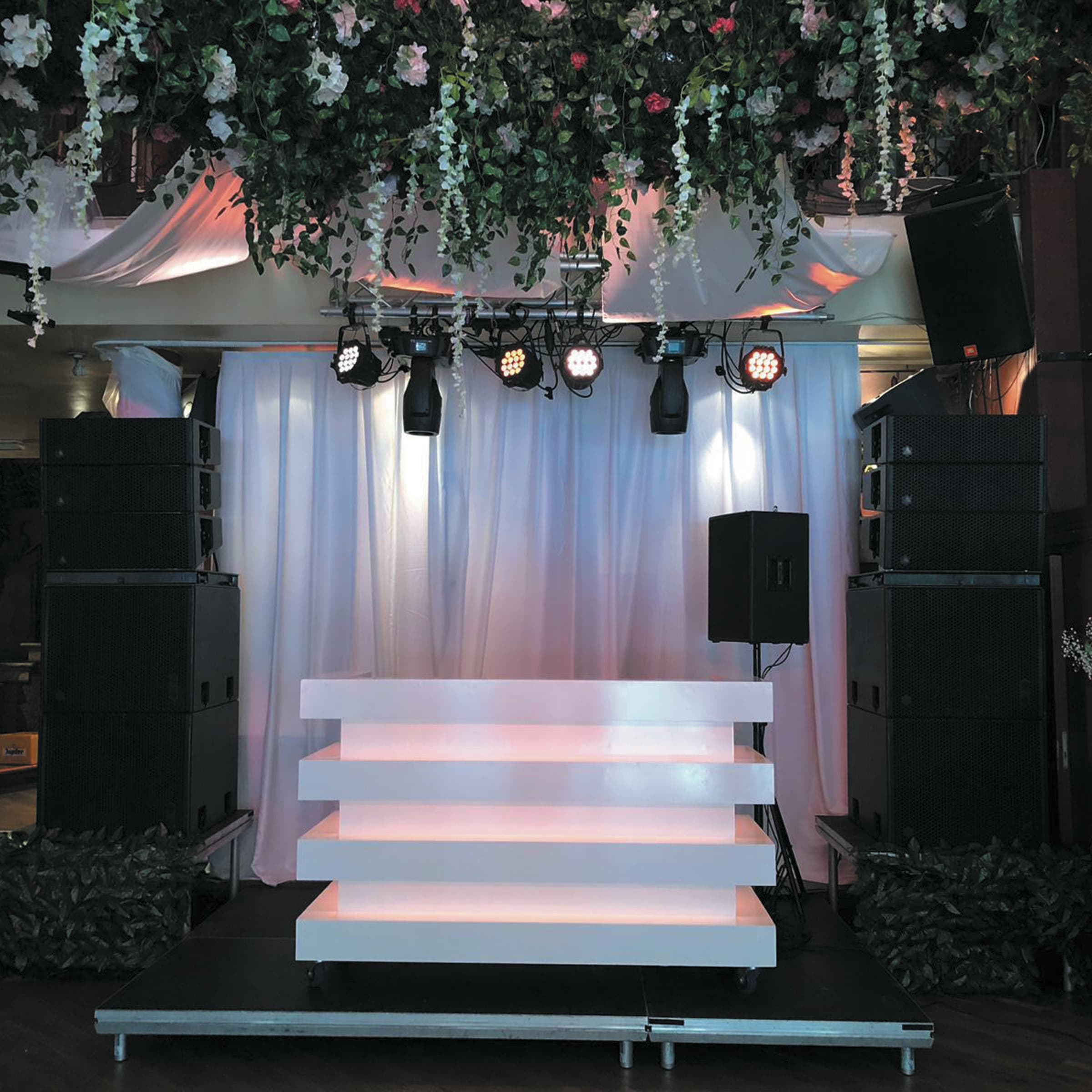 DJ podium met bloemeninstallatie, stage lighting en speakers - festival sfeer