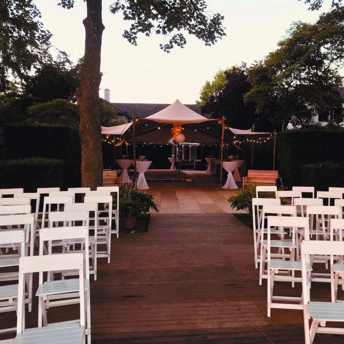 Sailcloth tent bij zonsondergang met statafels en ceremony chairs